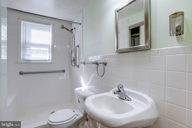 bathroom featuring sink, tiled shower, tile walls, and toilet