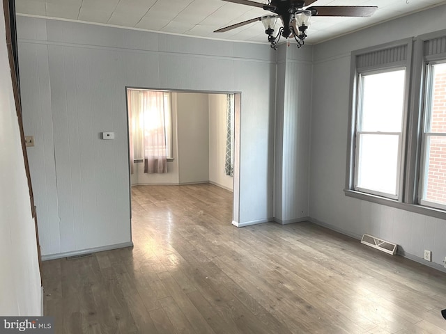 unfurnished room with hardwood / wood-style floors, a healthy amount of sunlight, and ceiling fan