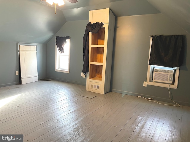 additional living space with cooling unit, ceiling fan, vaulted ceiling, and light hardwood / wood-style floors