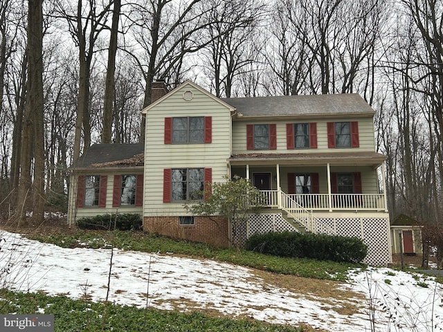 view of front facade featuring stairs, a porch, and a chimney