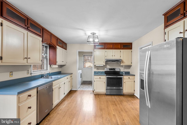 kitchen featuring stainless steel appliances, light wood-style flooring, glass insert cabinets, a sink, and under cabinet range hood