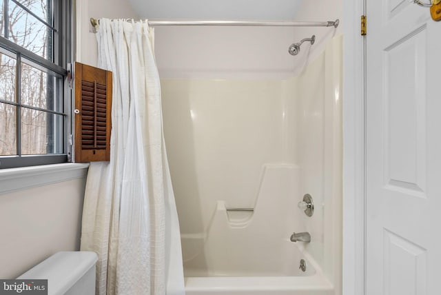 bathroom featuring toilet and shower / tub combo with curtain