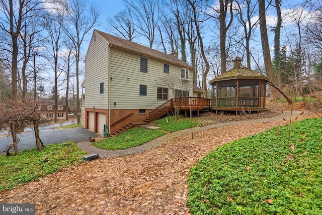 rear view of house featuring aphalt driveway, a gazebo, a deck, a garage, and stairs