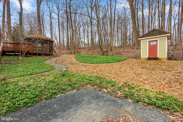 view of yard featuring a storage shed, a deck, and an outdoor structure