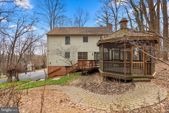 rear view of property featuring a gazebo and a wooden deck