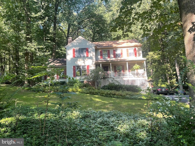 view of front of property featuring a front yard, covered porch, and a chimney