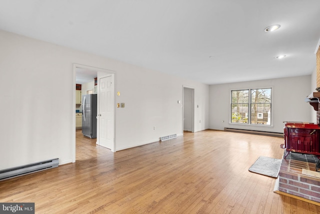 living room featuring a baseboard heating unit, baseboards, visible vents, and light wood-style floors