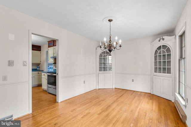 dining area featuring visible vents, baseboard heating, a chandelier, light wood-type flooring, and baseboards