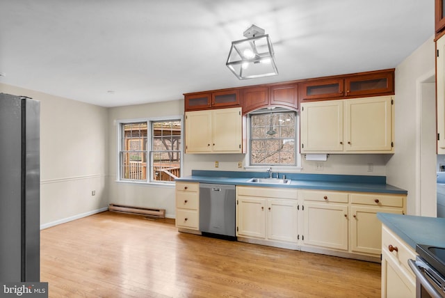 kitchen featuring stainless steel appliances, baseboard heating, light wood-style floors, glass insert cabinets, and a sink