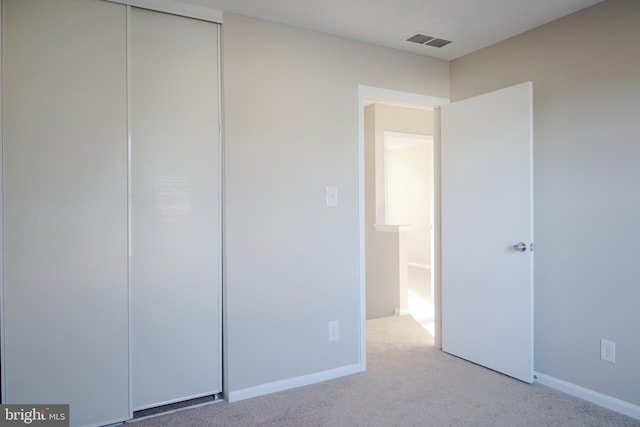 unfurnished bedroom featuring light colored carpet and a closet