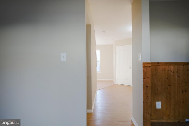 corridor with wooden walls and light hardwood / wood-style floors