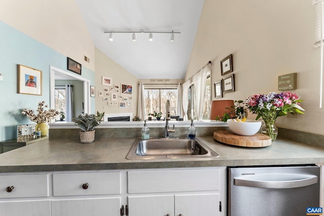 kitchen featuring lofted ceiling, sink, white cabinets, stainless steel dishwasher, and kitchen peninsula