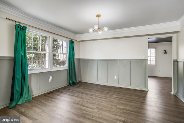 empty room with dark wood-type flooring, ornamental molding, and a chandelier