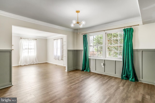 spare room featuring hardwood / wood-style flooring, ornamental molding, and a notable chandelier