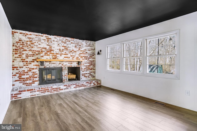 unfurnished living room featuring a brick fireplace and hardwood / wood-style floors