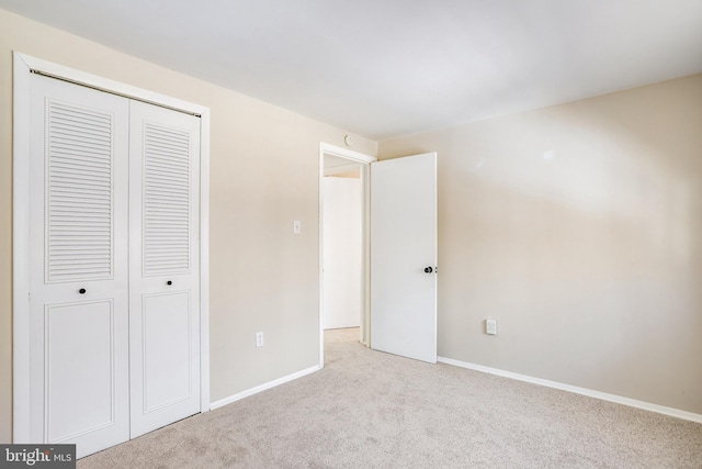 unfurnished bedroom featuring light colored carpet and a closet