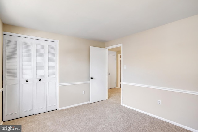 unfurnished bedroom featuring light colored carpet and a closet