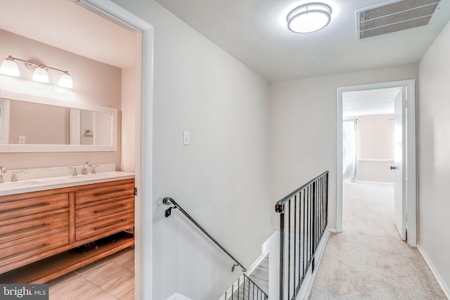 corridor with sink and light colored carpet