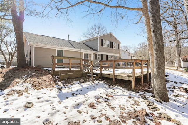 snow covered property with a garage and a wooden deck