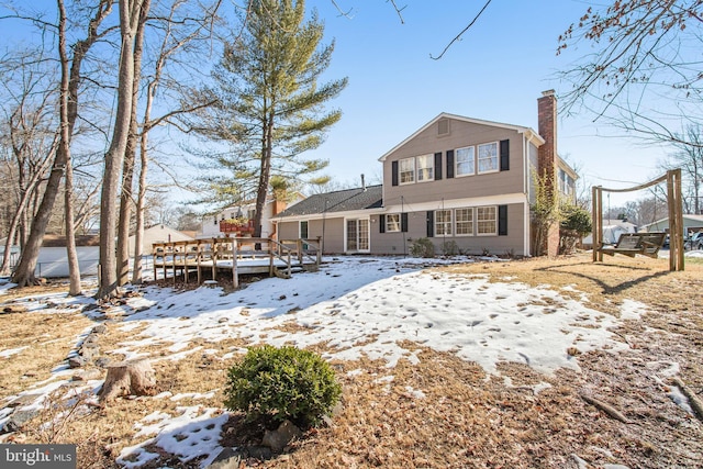 snow covered house featuring a wooden deck