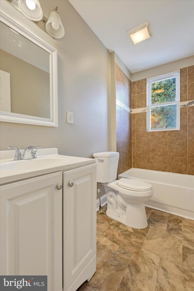 full bathroom featuring vanity, tiled shower / bath, and toilet