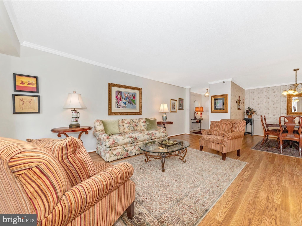 living room with a notable chandelier, ornamental molding, and light hardwood / wood-style floors