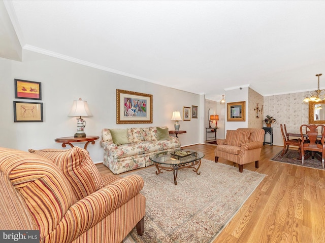 living room with a notable chandelier, ornamental molding, and light hardwood / wood-style floors