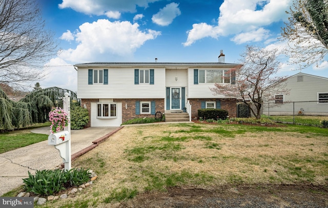 split foyer home with fence, a chimney, a front lawn, and brick siding