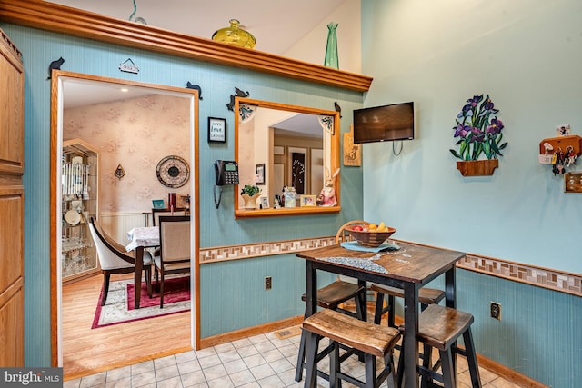 dining space with light tile patterned flooring and wainscoting