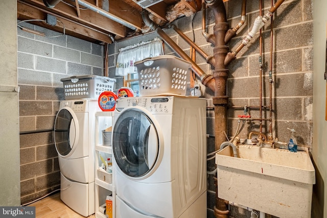laundry room with separate washer and dryer, laundry area, a sink, and concrete block wall