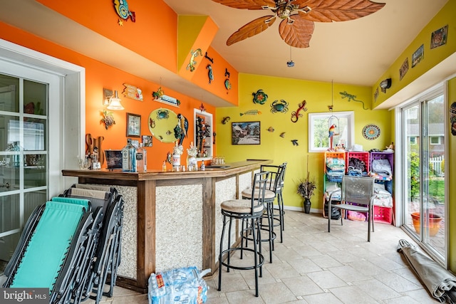 bar featuring bar, baseboards, a ceiling fan, and lofted ceiling