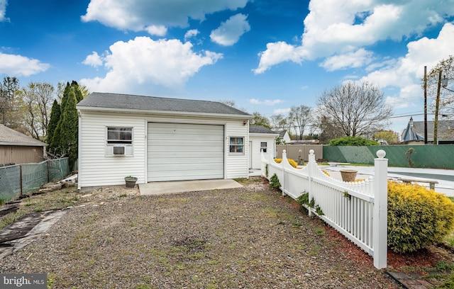 garage featuring fence and gravel driveway
