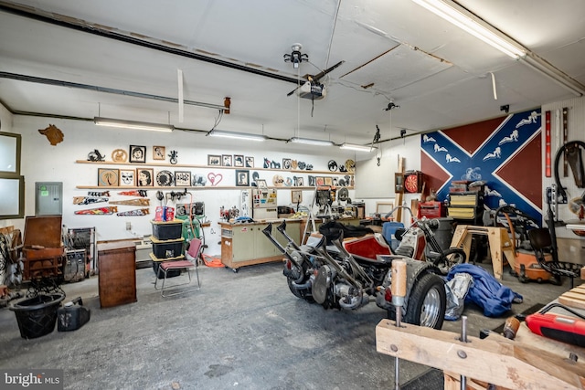 garage with a workshop area, a garage door opener, and electric panel