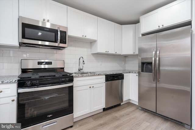 kitchen featuring light stone counters, appliances with stainless steel finishes, sink, and white cabinets