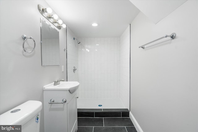 bathroom with tile patterned flooring, vanity, toilet, and tiled shower