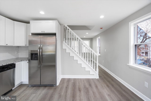 kitchen featuring light stone counters, tasteful backsplash, white cabinets, and appliances with stainless steel finishes