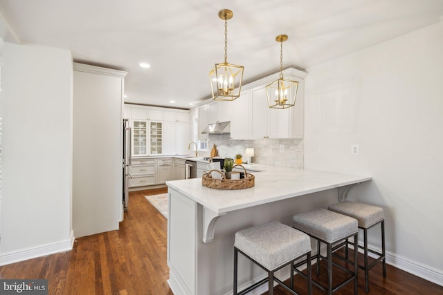 kitchen with hanging light fixtures, white cabinets, a kitchen bar, and kitchen peninsula