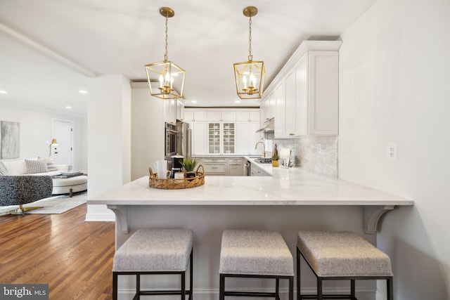 kitchen featuring white cabinetry, decorative light fixtures, a kitchen breakfast bar, and kitchen peninsula