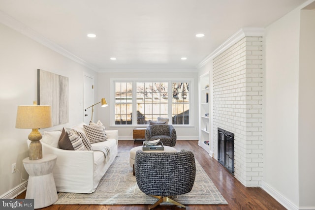 living room featuring crown molding, built in shelves, a fireplace, and hardwood / wood-style flooring