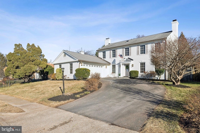 colonial house with a garage and a front lawn