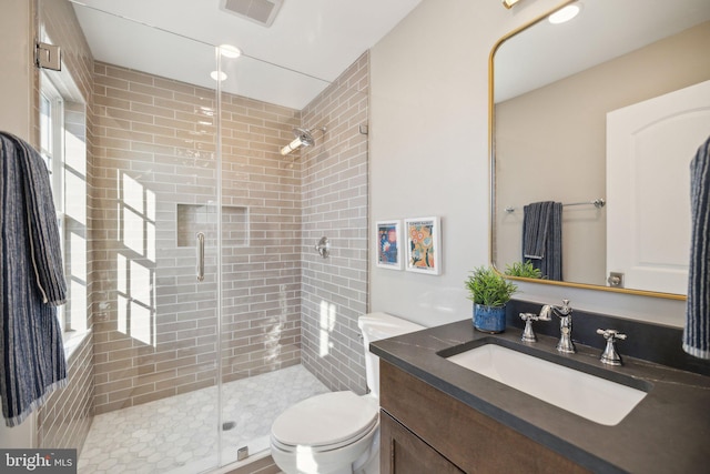 bathroom with a shower with door, vanity, and toilet