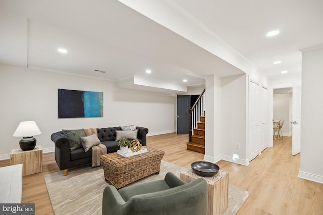 living room with ornamental molding and light hardwood / wood-style flooring