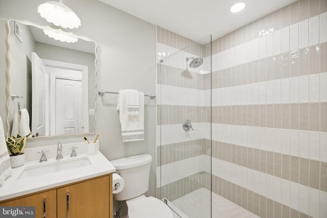 bathroom featuring toilet, vanity, and a shower with shower door