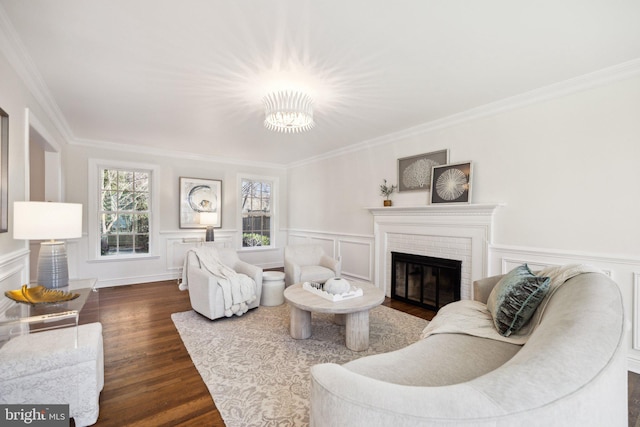 living room with dark wood-type flooring, ornamental molding, and a brick fireplace