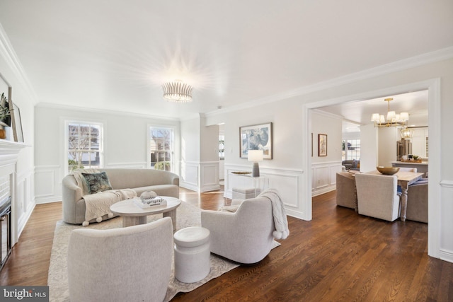 living room with an inviting chandelier, plenty of natural light, ornamental molding, and dark hardwood / wood-style floors