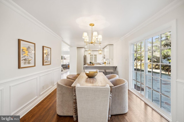 dining room with an inviting chandelier, ornamental molding, and dark hardwood / wood-style floors