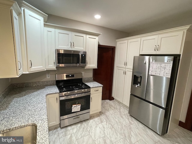 kitchen with stainless steel appliances, light stone countertops, and white cabinets