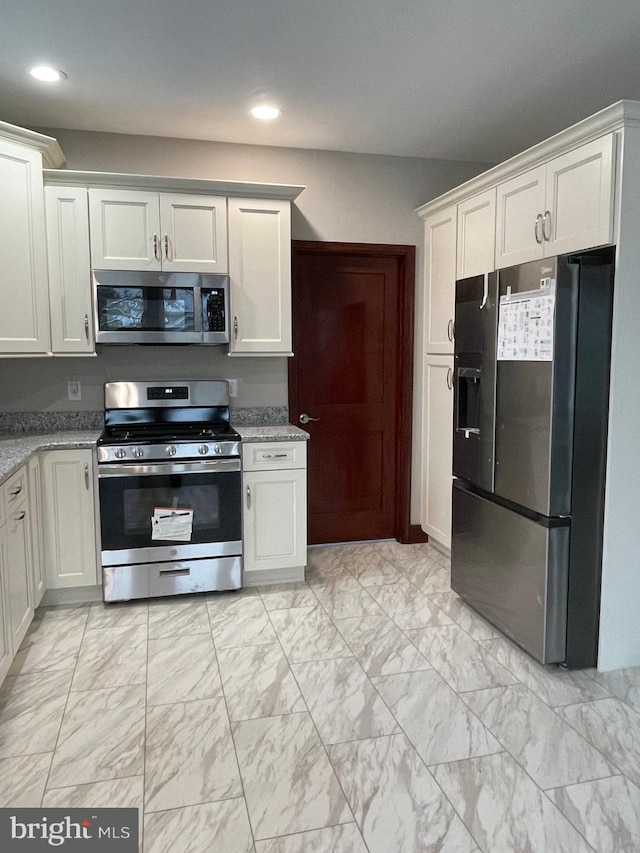 kitchen featuring stainless steel appliances, light stone countertops, and white cabinets