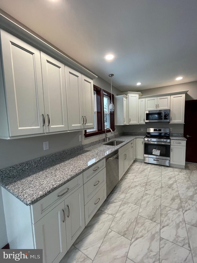 kitchen featuring sink, decorative light fixtures, stainless steel appliances, and dark stone counters