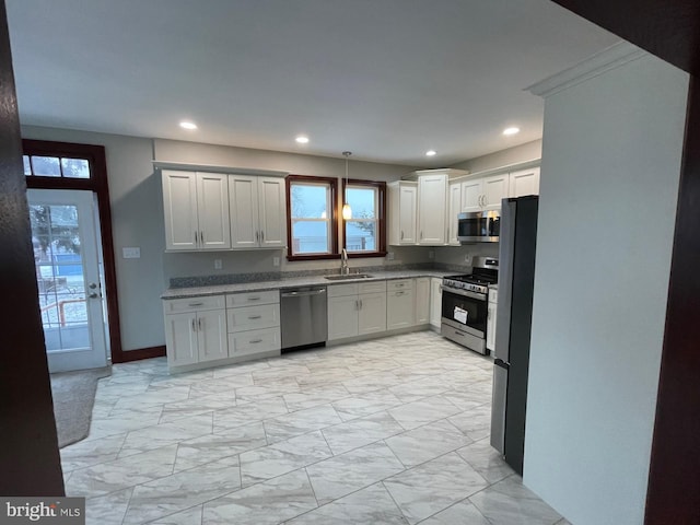 kitchen with pendant lighting, sink, stainless steel appliances, and white cabinets